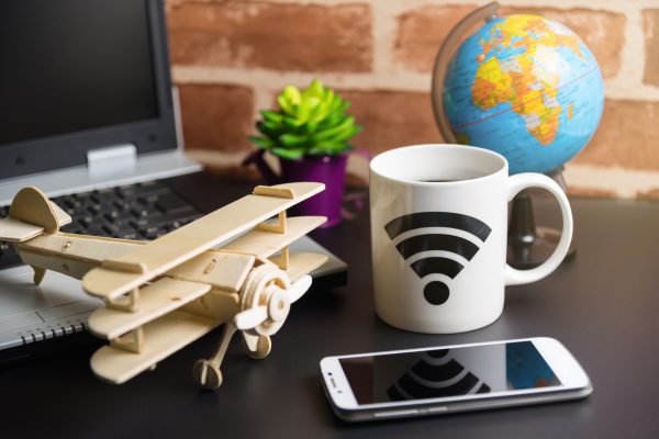 Table of office stuff Business man with Laptop, Wireless mouse, Smart phone, Toy wooden plane and Coffee Cup WIFI symbol.Concept office Business man workplace.